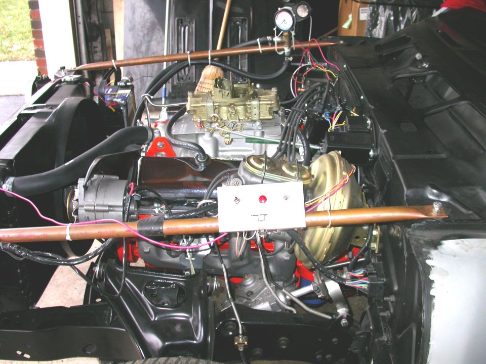 Engine bay showing V8 engine, carburetor, brake booster, and wiring