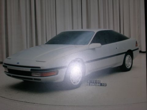 1997 Ford Probe - A white coupe with a dark roof and tinted windows is displayed against a curtained background.