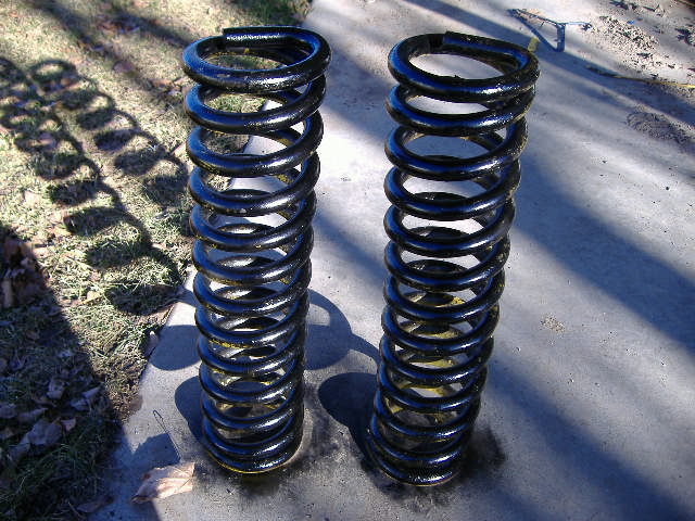 Two black coil springs with yellow bands on a concrete surface