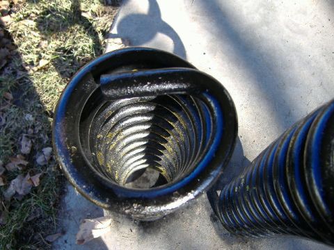 1979 Ford Bronco - A close-up view of a black coil spring, likely a suspension component, with visible yellow and blue markings.