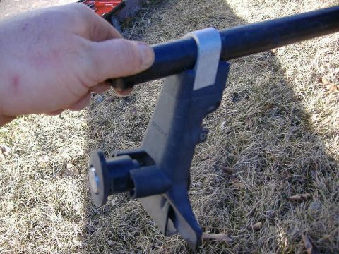 1979 Ford Bronco - A hand holds a black roof rack part with a metal strap attached to a dark bar.