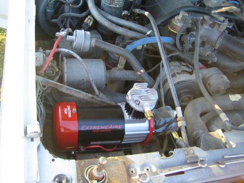 1990 Ford Bronco - ExtremeAire High Output onboard air compressor is mounted under the hood among engine hoses and wiring.