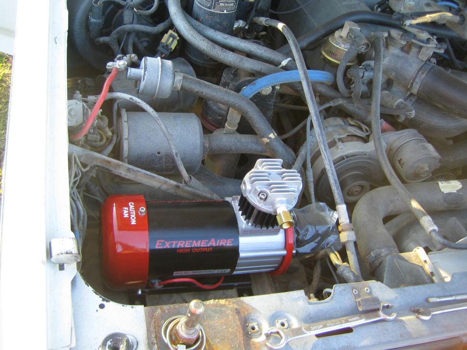 Red and black ExtremeAire High Output air compressor mounted in an engine bay