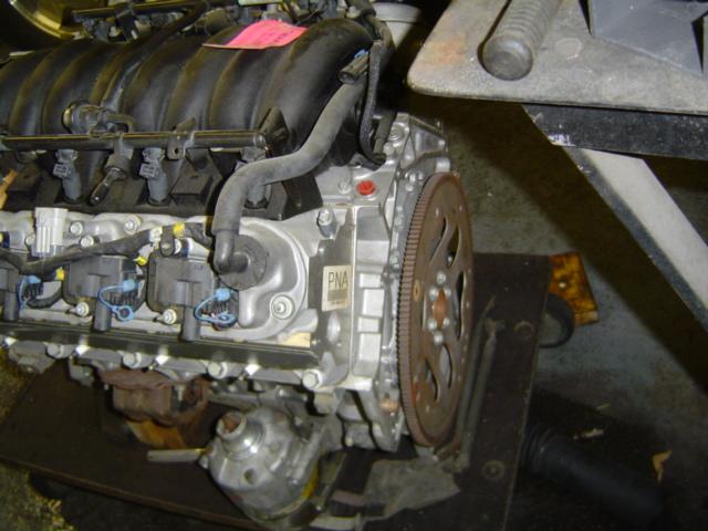 engine assembly on a stand, showing intake manifold, fuel injectors, and flywheel