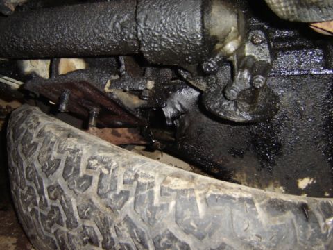 1992 Ford Bronco - Close-up view of a greasy vehicle undercarriage, with a tire visible.