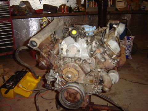 1992 Ford Bronco - Engine assembly shown in a workshop setting with tools and parts.