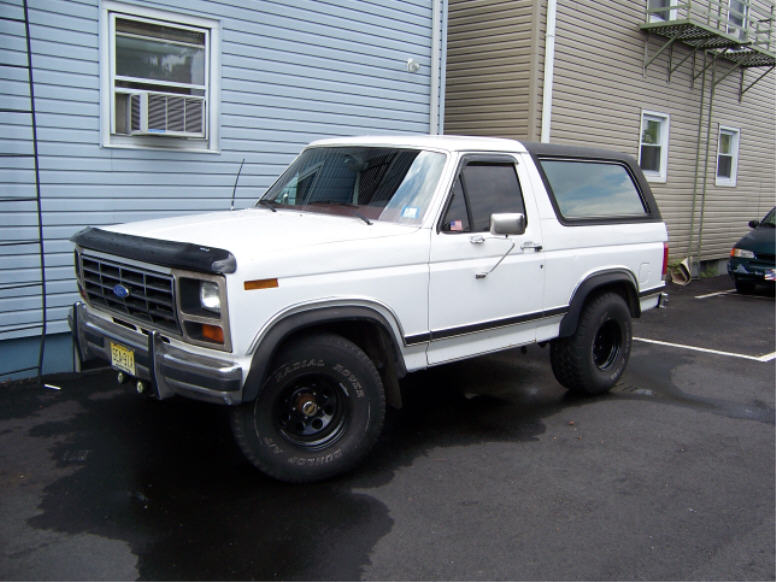 White 1986 Ford Bronco parked outside a building, black trim, black wheels