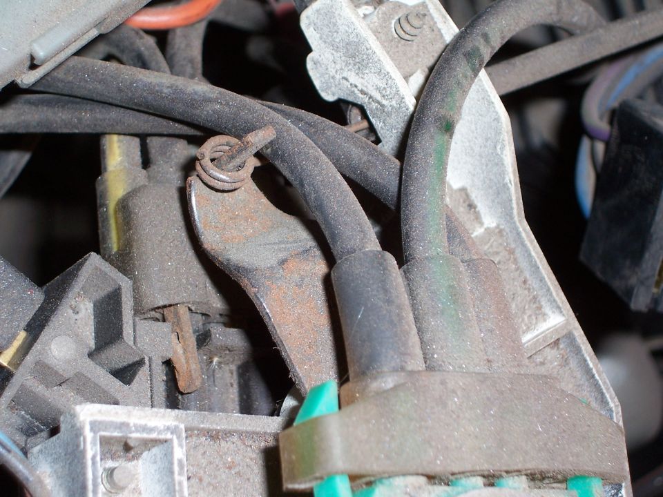 Close-up of dusty automotive wiring and metal bracket with a coiled spring