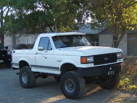 1988 Ford Bronco - This lifted white Ford Bronco has a custom front bumper and a spare tire mounted on the rear.