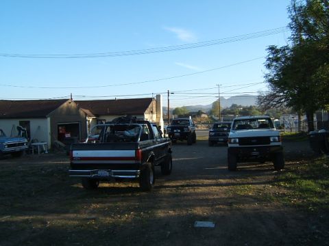 1988 Ford Bronco - A black 1988 Ford Bronco is parked in a lot with several other trucks and SUVs under a clear blue sky.