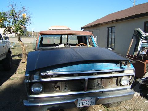 1988 Ford Bronco - A blue and rust Ford F-Series truck sits in a yard with its hood open, displaying a California license plate.