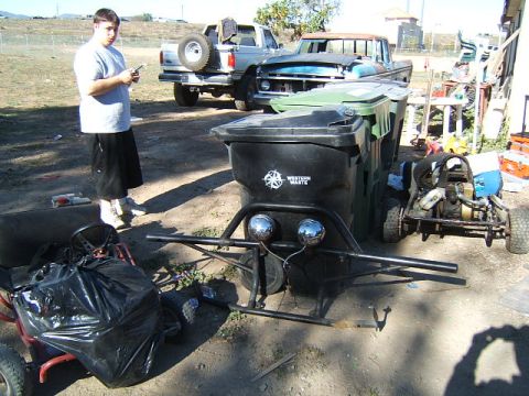 1988 Ford Bronco - A scene with a go-kart and two trucks, one with a spare tire mounted on the back.