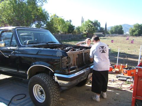 1988 Ford Bronco - Working on a 1988 Ford Bronco with the hood up, two people are present.