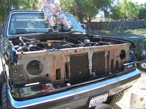 1988 Ford Bronco - Disassembled front end of a black Ford Bronco, with a person sitting on the hood.