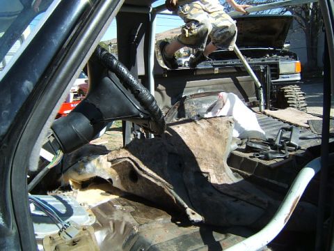 1988 Ford Bronco - Interior view of a vehicle undergoing disassembly, with a person climbing over the rear bed.