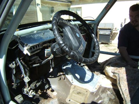 1988 Ford Bronco - The interior of a 1988 Ford Bronco shows a custom steering wheel and roll cage, with the dashboard partially disassembled.