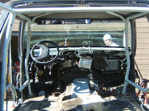 1988 Ford Bronco - The interior of a vehicle is shown, a roll cage and a partially disassembled dashboard.
