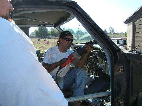 1988 Ford Bronco - Man cuts into vehicle interior with a reciprocating saw.