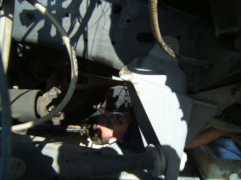 1988 Ford Bronco - A mechanic is working on the undercarriage of a vehicle, surrounded by mechanical parts and shadows.