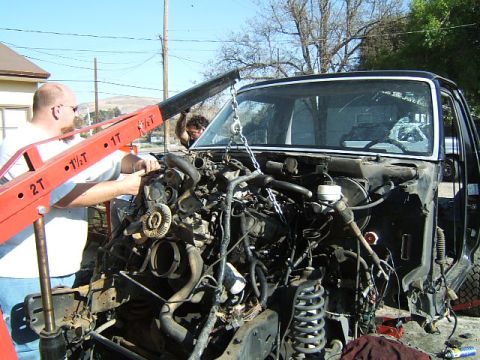 1988 Ford Bronco - Engine removal in progress on a truck, with a hoist lifting the engine out of the engine bay.