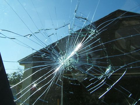 1988 Ford Bronco - Looking through a severely cracked windshield at a building under a clear blue sky.