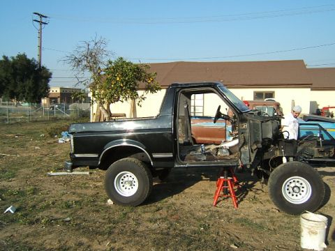 1988 Ford Bronco - 1988 Ford Bronco body undergoing work, supported by jack stands with doors removed.