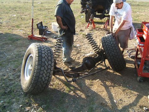 1988 Ford Bronco - Two men work on a vehicle's front axle assembly, which has been removed from the chassis.
