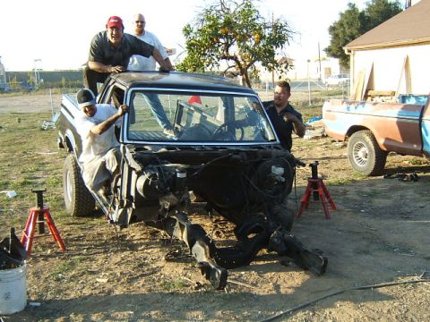 1988 Ford Bronco - Three men examine a disassembled black Ford Bronco, with a partial view of a second truck in the background.