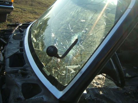 1988 Ford Bronco - Close-up of a broken windshield and gear shifter, with another vehicle in the background.