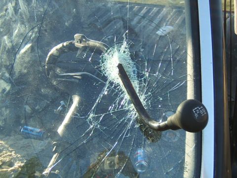 1988 Ford Bronco - The interior of a vehicle shows a cracked windshield and a four-wheel drive shifter.