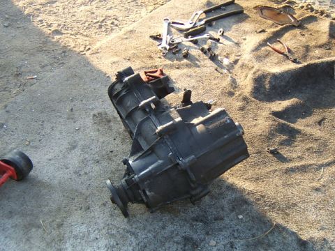 1988 Ford Bronco - Transmission assembly and tools laid out on the ground for repair or maintenance.