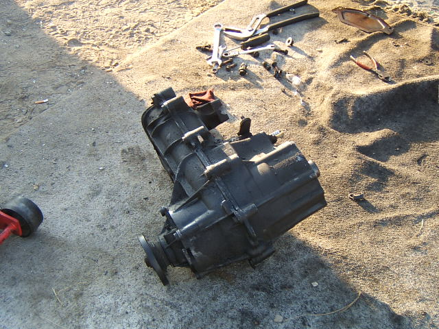 Black transmission assembly and various tools on sand and concrete