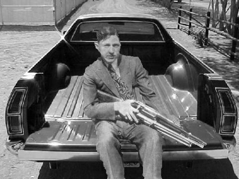 2002 Ford Crown Victoria - A man sits in the bed of a pickup truck holding a shotgun, with a fence and trees in the background.