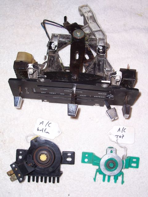 1978 Ford Bronco - A removed heater and A/C control head laid on carpet, its faceplate reading FAN HI/LO, OFF, VENT, A/C, HEAT, DEFROST and COOL-WARM temperat…