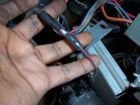 1978 Ford Bronco - Close-up of a hand manipulating electrical connectors and wires within a vehicle's interior.