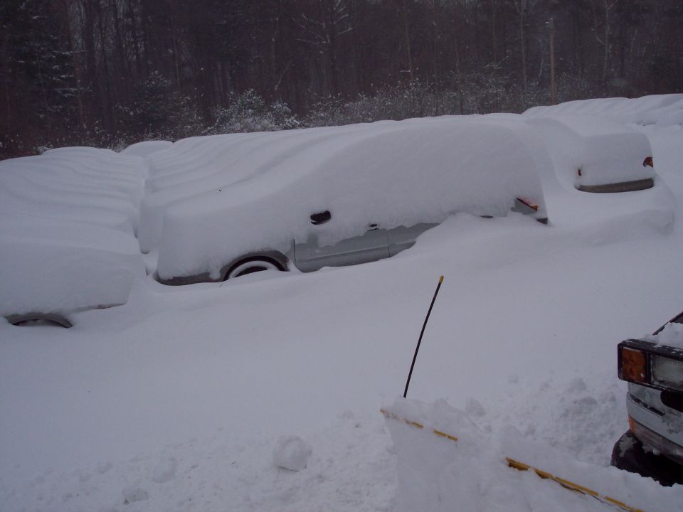 Several cars buried under deep snow, with only the tops of some visible