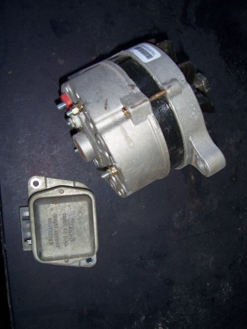 1983 Ford Bronco - An alternator and voltage regulator are shown together on a dark surface.