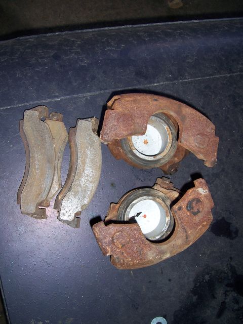 1983 Ford Bronco - Pair of used brake calipers and pads, showing significant rust and wear.