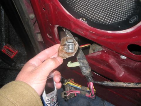 1991 Ford Bronco - Close-up of a car's interior door panel wiring harness with a hand holding a connector.