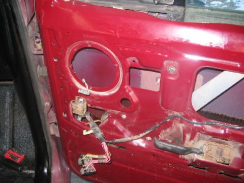 1991 Ford Bronco - Interior view of a red door panel from a 1991 Ford Bronco, showing the speaker cutout and exposed wiring.