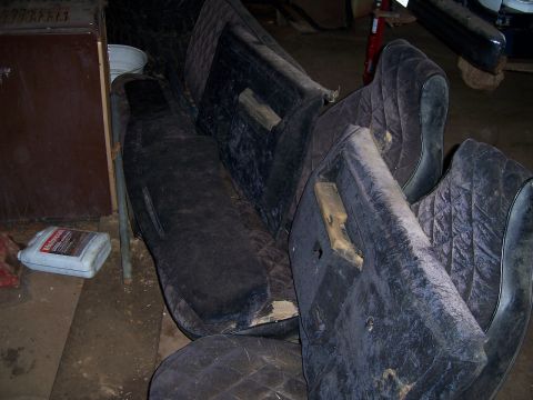 1983 Ford Bronco - Several dark, quilted car door panels are stacked together in a cluttered space.