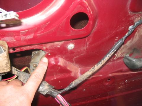 1991 Ford Bronco - A finger points to the wiring and latch mechanism inside a red car door, suggesting a repair or inspection.
