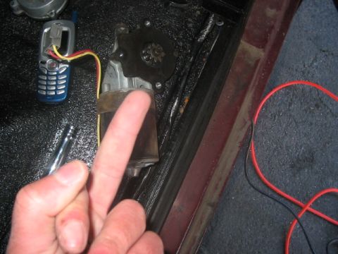 1991 Ford Bronco - Window motor and wiring are visible next to a cell phone and a tool.