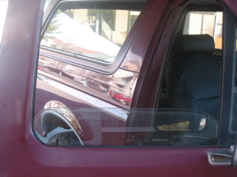 1991 Ford Bronco - Interior view of a maroon SUV, showing dark seats and a reflection on the side window.