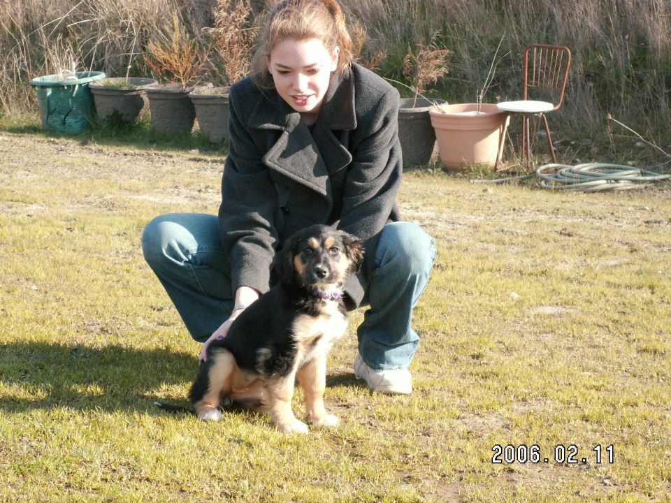 Woman crouching with a dog in a grassy outdoor setting
