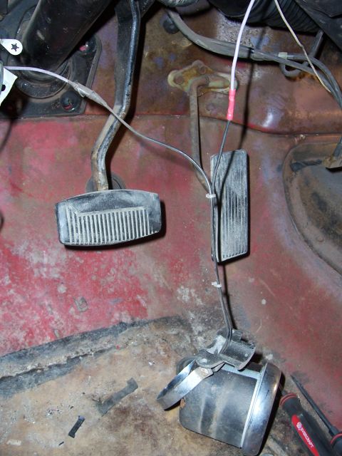 1978 Ford Bronco - Close-up view of the vehicle's interior floor, showing pedals and wiring, with visible rust and wear.