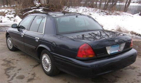 1999 Ford Crown Victoria - A dark blue 1998 Ford Crown Victoria is viewed from the rear three-quarter angle on a paved surface with snow in the background.