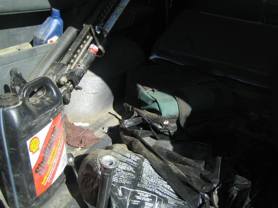 Hi-Lift type jack and Shell oil jug stored behind a folded vehicle seat