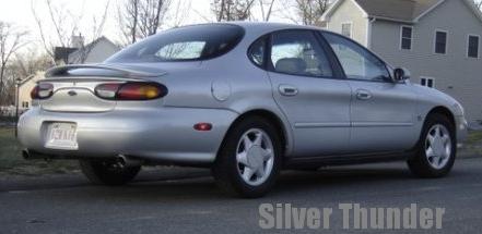 1999 Ford Taurus - Silver 1999 Ford Taurus sedan parked on a street, showing its rear and side profile.