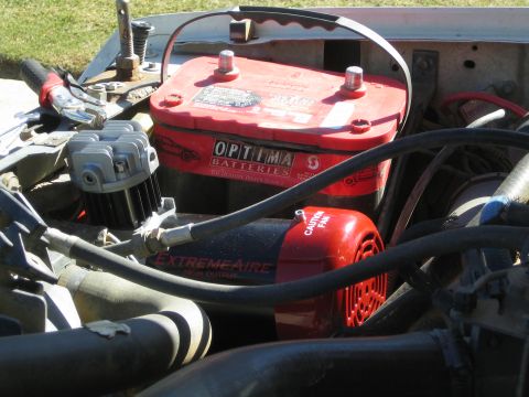 1990 Ford Bronco - red Optima battery sits beside a red and black ExtremeAire compressor among hoses and wiring in an engine bay.